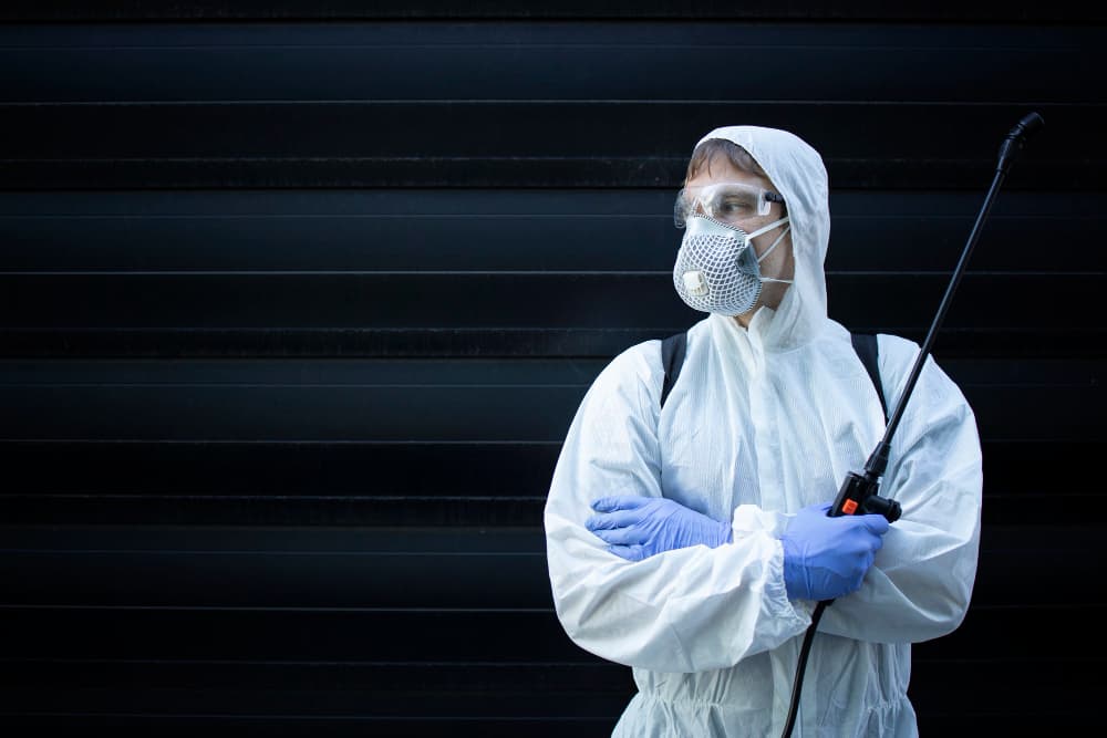 Pest control specialist in protective equipment working indoors